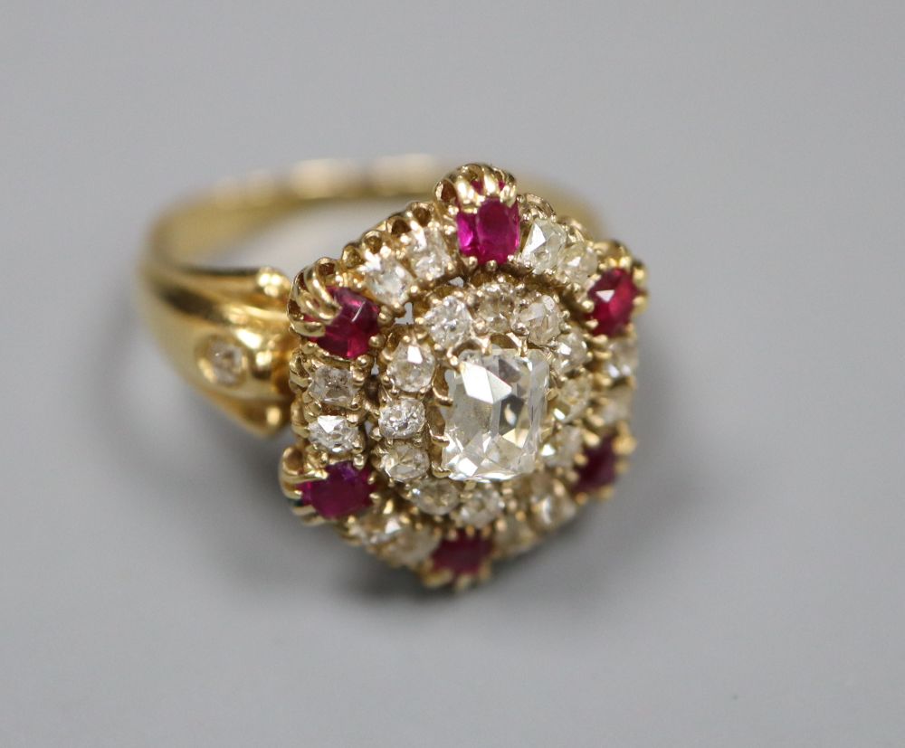 A Victorian style yellow metal ruby and diamond oval cluster ring, with central rectangular cushion cut stone, size L, gross
